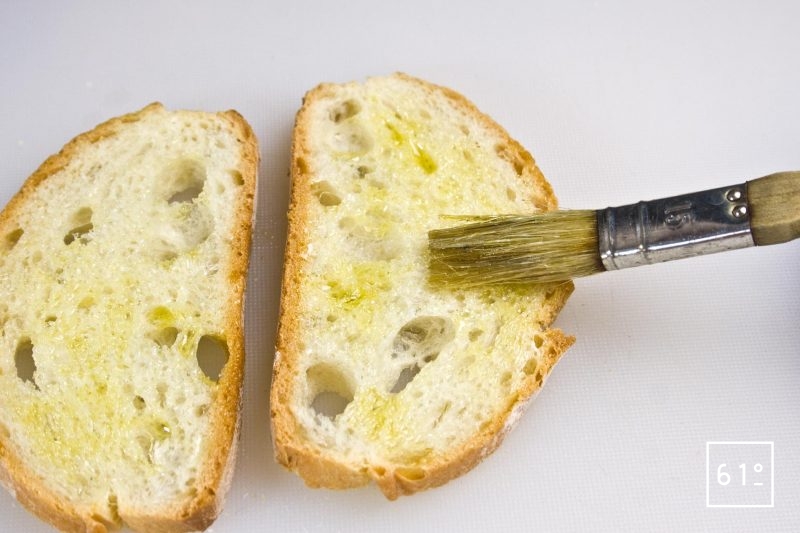 Badigeonner les tranches de pain avec de l'huile d'olive avant de les faire griller